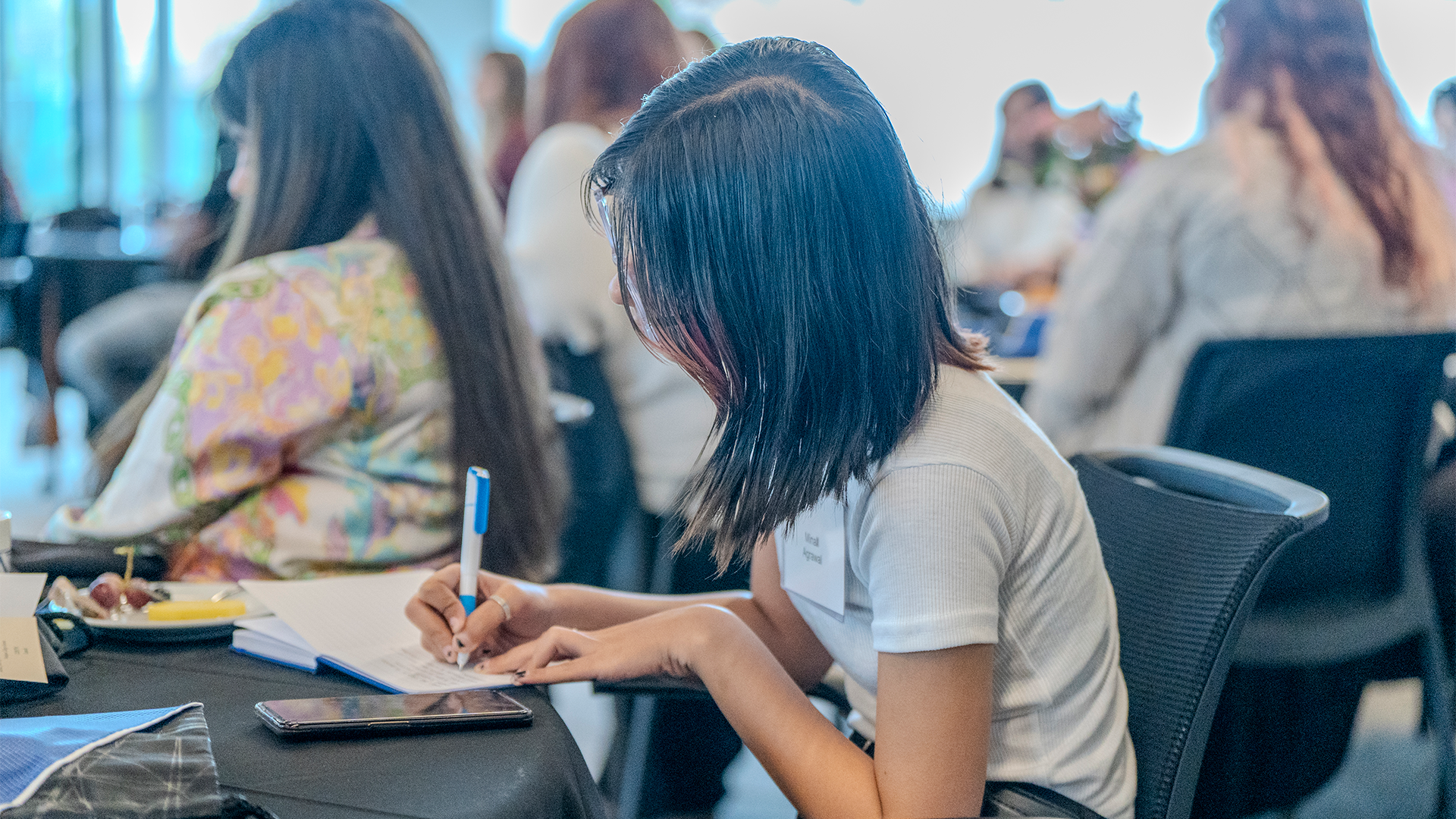 Solve Problems Student at a table, taking notes in notebook